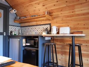 金洛赫利文Coe Pod, West Highland Way Holidays的厨房设有木墙和带凳子的台面。