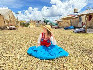普诺Hotel - Titicaca Dora的坐在干草上穿着蓝色衣服的小女孩