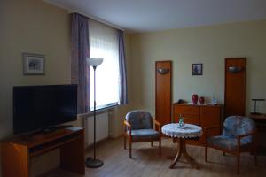哈根莱克斯酒店的客厅配有电视、2把椅子和1张桌子