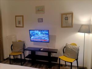 雅典Kallimarmaro Cozy的一间设有两把椅子和一张桌子的房间,墙上配有电视