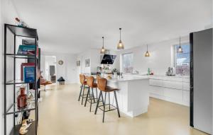 SundsGorgeous Home In Sunds With Kitchen的一间厨房,配有白色橱柜和一个带凳子的酒吧