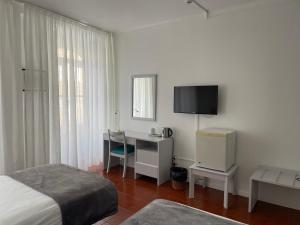 英雄港Hotel Ilha的一间卧室配有一张床、一张书桌和一台电视。