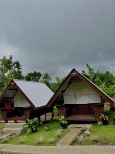 BatuanROCA'S HOMESTAY Backpackers Chalet Bohol的金属屋顶和草屋