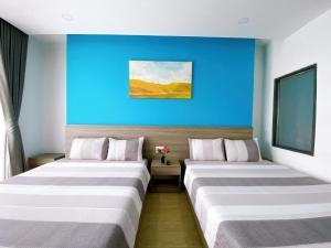 芽庄HÀO PHÁT HOTEL NHA TRANG的蓝色墙壁的酒店客房内的两张床