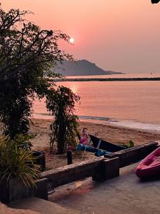 科隆万Sea Sand House Resort的日落时坐在海滩吊床上的女人