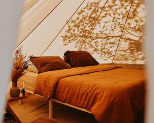 科尔斯湾Numie - Freycinet Peninsula - Glamping的配有橙色棉被和枕头的床