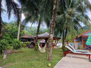 蔻立Khaolak Banana Bungalow的一个带吊床和两棵棕榈树的度假村