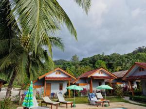蔻立Khaolak Banana Bungalow的一个带椅子和遮阳伞的度假村和棕榈树