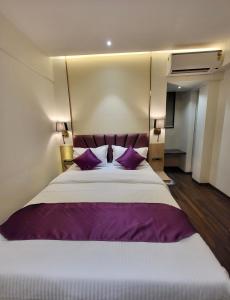 孟买Vishal Hall的一间卧室配有一张带紫色枕头的大床