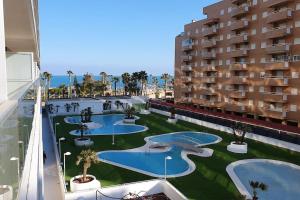 奥罗佩萨德尔马Apartamento en primerisima linia de playa的享有带游泳池和棕榈树的公寓大楼的正面景色