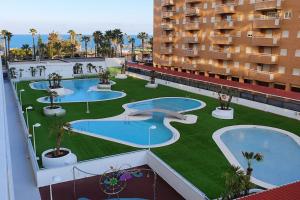 奥罗佩萨德尔马Apartamento en primerisima linia de playa的享有公寓大楼的空中景致,设有3个游泳池