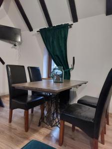 希维博津Apartament Krawcownia的餐桌、黑色椅子和绿帘