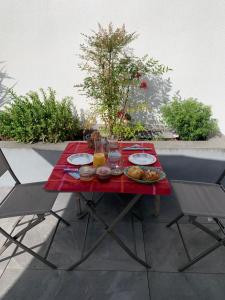 拉罗谢尔Maison M, chambre privée accès jardin piscine et jacuzzi près de La Rochelle的露台上的红色桌子,上面放着盘子
