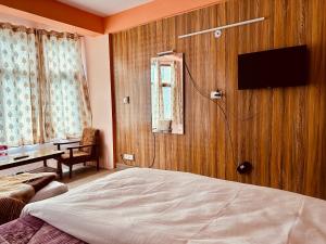 马拉里Hotel D Kanchan Manali的一间卧室配有一张床,墙上配有电视