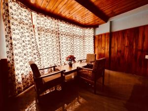 马拉里Hotel D Kanchan Manali的客房设有桌椅和窗户。