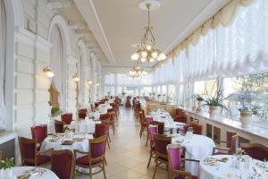 卡罗维发利布里斯托宫酒店的餐厅设有白色的桌椅和窗户。