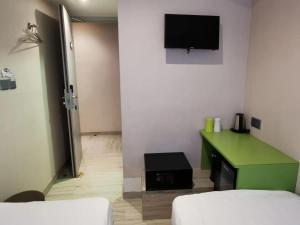 香港Pop E INN-B&B的客房设有绿色的办公桌和墙上的电视。