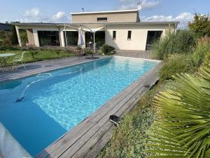 奥内莱沙托Villa contemporaine avec piscine sur 4000 m2 à Rodez 9 personnes的一座带木甲板的游泳池,位于一座房子旁边