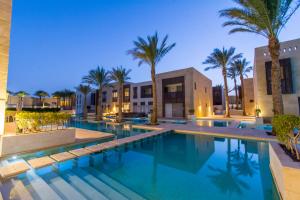 赫尔格达Nayah Stays, Beautiful 3-bedroom vacation home with lovely pool的一座棕榈树和建筑游泳池
