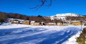 O Busto Aldea Rural, Apartamento HORNO 2的一片雪覆盖的田野,有房子和山