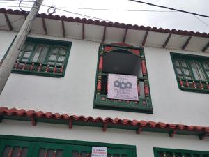 蒙圭ApartaHotel Monguí的一座建筑,上面有绿色的窗户和标志