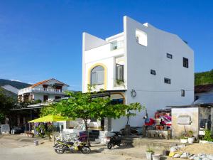 Tân HiệpChàm’s Corner Lookout Homestay & Restaurant的一座白色的建筑,前面停有摩托车