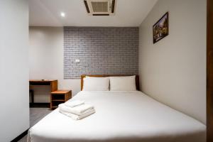 曼谷GO INN Sukhumvit 20 Bts Asoke-Phrom Phong的砖墙房间内的一张白色床