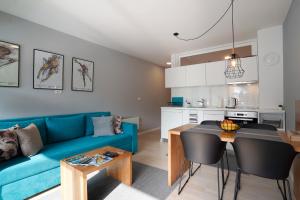 别拉什尼察naTURE apartment Bjelasnica的客厅配有蓝色的沙发和桌子