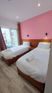 法鲁康达住宅旅馆的配有两张床的带粉红色墙壁的客房