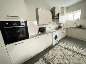 艾纯查姆Central Mews House Altrincham的厨房配有白色橱柜、洗衣机和烘干机