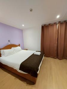 法鲁康达住宅旅馆的卧室配有一张带黑色毯子的大型白色床。