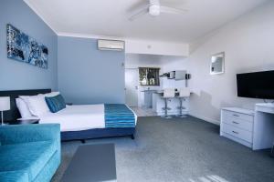 赫维湾赫维湾海滩汽车旅馆的一间卧室配有一张床、一张沙发和一台电视。