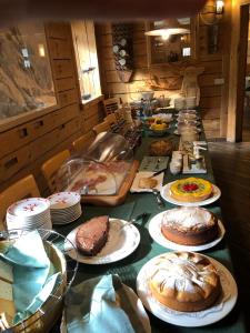 瓦尔布鲁纳Valbruna Inn Bed & Breakfast的长桌,盘子里放蛋糕和蛋糕