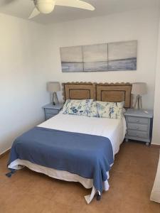 萨阿拉德洛斯阿图内斯Precioso ático duplex en Atlanterra Playa. Zahara的一间卧室配有一张带蓝色床单的床和2个床头柜。