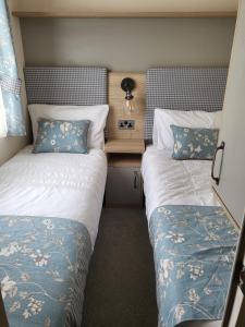 Porchfieldluxury new 3 bed caravan with stunning sea view on private beach in Thorness bay的一间卧室配有两张床和一张带台灯的桌子