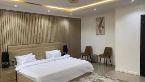 拉各斯Mansal Luxury Apartments的一间卧室配有一张大床和两把椅子
