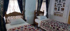 布哈拉Barlos XVIII的配有窗帘和窗户的客房内的两张床