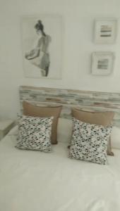 萨阿拉德洛斯阿图内斯Zaharaiso luz的床上的2个枕头,墙上挂着一张照片