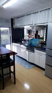 Arazato宮古島ゲストハウス　マウイ的厨房配有白色橱柜、木桌和桌子。