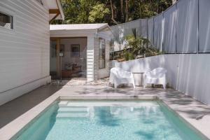 萨福克公园Blackbutt House - Luxe Family Retreat With Pool的一个带白色椅子的游泳池以及一座房子
