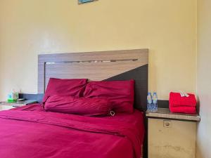 SampitGreenville Hotel Mitra RedDoorz的一张铺有红色床单的床和木制床头板