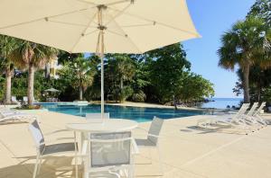 尼格瑞尔Stunning Ocean View的游泳池旁配有遮阳伞的桌椅