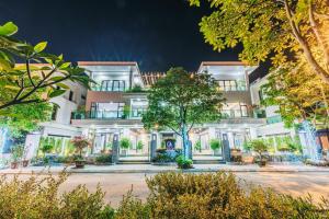 岑山Villa Centrel FLC Sầm Sơn Vị Trí Gần Bãi Biển的前面有树木的白色大建筑