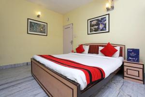 Ālīpur阿里波利旅馆的一间卧室配有一张带红色枕头的大床