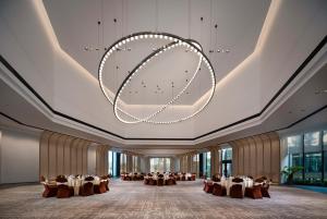 永修吴城远洲酒店的一个带桌椅和大吊灯的大型宴会厅