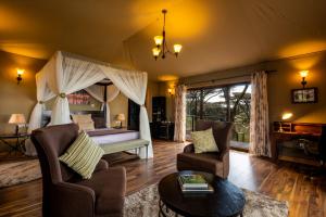 恩戈罗恩戈罗Lions Paw Ngorongoro的一间卧室设有一张床和一间客厅。