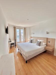 坦耶尔米塔格Hôtel Les Deux Coteaux的白色卧室配有一张大床和一张书桌