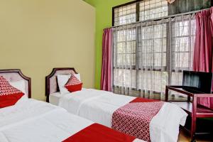 北干巴鲁OYO 92331 Rindu Sempadan Cottage的一间卧室设有两张床和窗户。