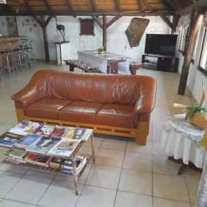 奥卡汉贾Ombo Rest Camp的客厅里一张棕色的皮沙发,配有桌子