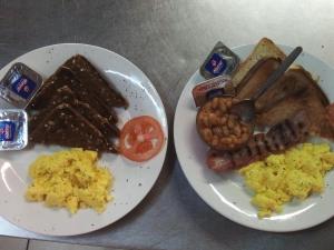 奥卡汉贾Ombo Rest Camp的两盘早餐食品,包括鸡蛋香肠和烤面包
